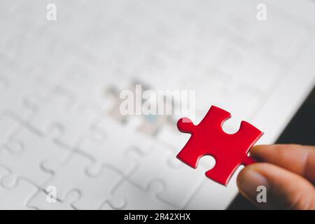 Business woman person hand holding puzzle piece idea for strategy and solution. Closeup part of one red jigsaw connect together. Concept of join coope Stock Photo