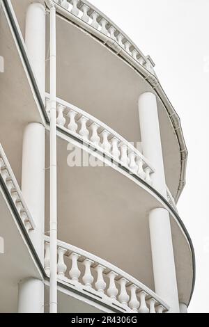 Old fashioned building with multi level semi circle terraces decorated with classic style white fences and columns. Vintage exterior of hotel Stock Photo