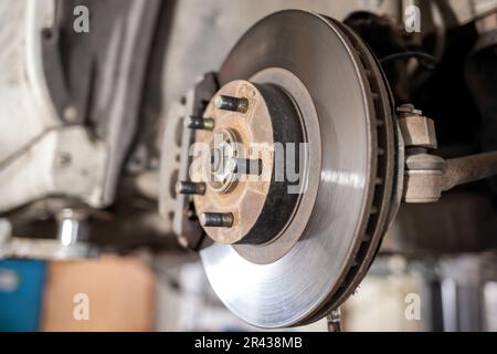Disc brake of the vehicle for repair, in process of new tire replacement. Car brake repairing in garage.Suspension of car for maintenance brakes and s Stock Photo