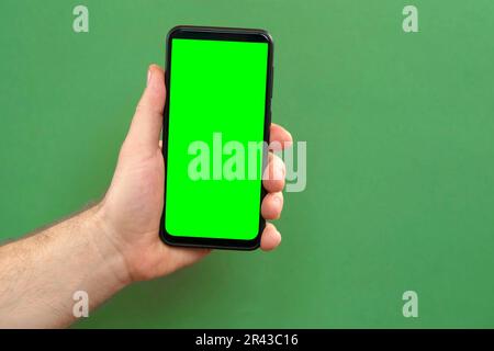 Young man hand use smartphone with green screen on green background. Gestures pack. Male hand touching, clicking, tapping swiping on black phone chrom Stock Photo