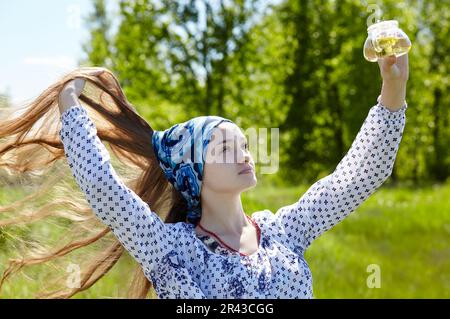Woman holding transparent teapot with herbal tea. Collects fresh green herbs harvest and make healthy tea. Blurred image, selective focus Stock Photo