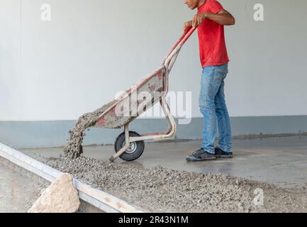Workers push cement trucks to pour the floor inside to prepare for tiling. Stock Photo