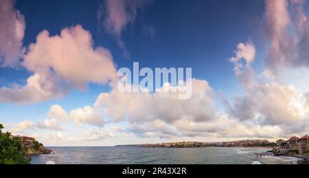 panorama with fluffy clouds on a blue sky in evening light. beautiful nature background at the sea. warm weather in velvet season Stock Photo