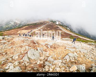 SNEZKA, GIANT MOUNTAINS - April 30, 2023.  Group of people in fog on Snezka in Krkonose National Park. Very bad weather. Stock Photo