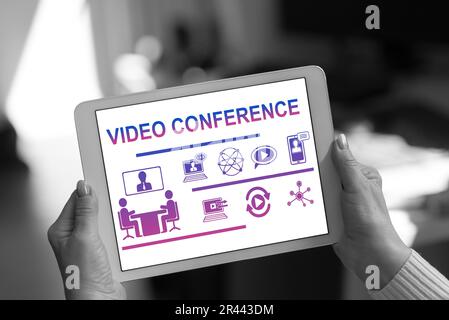 Video conference concept shown on a tablet held by a woman Stock Photo