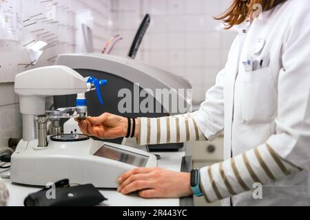 young oculist woman making eyeglass lens in an optician's workshop Stock Photo