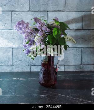 Still life with lilacs in a glass vase with a white dandelion and an ...