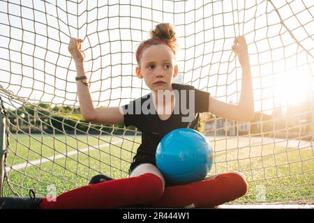 girl sat in a football goal waiting for her match to start Stock Photo