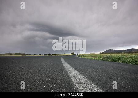low angle view white line country road below a gloomy sky in Sicily, Italy Stock Photo