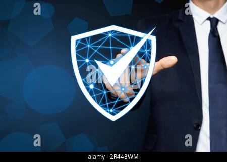 Anti-fraud security system. Man pointing at illustration of checkmark in shield on dark background, closeup. Space for text Stock Photo