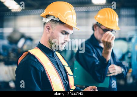 engineer male young worker teamwork working together in heavy industry with safety suit hard hat helmet Stock Photo