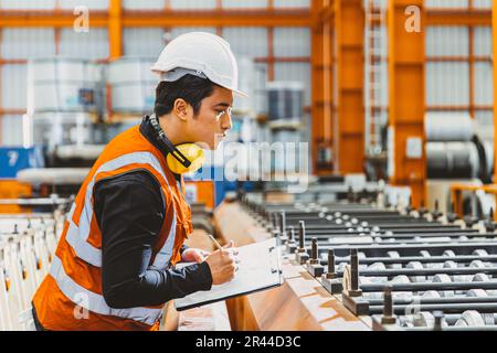 Young male engineer supervisor working QC in metal sheet manufactory work checking production line. Stock Photo