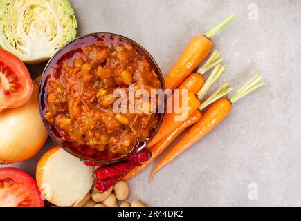 Traditional South African Chakalaka, popular spicy side dish or relish. On mottled grey with and fresh ingredients Stock Photo