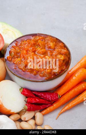 Traditional South African Chakalaka, popular spicy side dish or relish. On mottled grey with and fresh ingredients Stock Photo