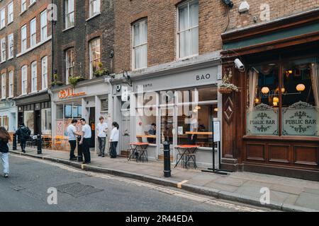 London, UK - April 13, 2023: Staff smoking outside Bao Taiwanese restaurant in Soho, an area of London famous for LGBTQ+ bars, restaurants and clubs. Stock Photo