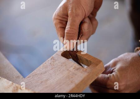 Capturing the skillful hands of a woodworker meticulously sanding and shaping the wood using sandpaper. Witness the artistry in the final stages of wo Stock Photo