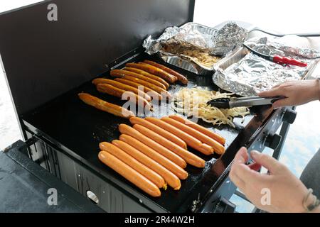 An unrecognisable person cooking a traditional australian bbq sausage sizzle, sausages cooking on a barbeque Stock Photo