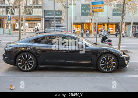 Side view of a black luxury Porsche Taycan Turbo S sports car parked on Paseo de Gracia Stock Photo