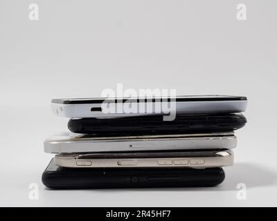 Damaged mobile phones. A bunch of broken smartphones. Used phones on a light background. Stock Photo