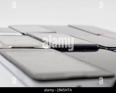 Damaged mobile phones. A bunch of broken smartphones. Used phones on a light background. Stock Photo