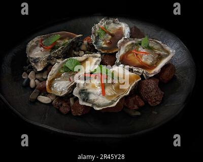 An assortment of fresh seafood, including clams, displayed on a bed of smooth pebbles Stock Photo