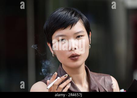 London, UK. 18th May, 2023. Model Kayako Higuchi smokes a cigarette as ...
