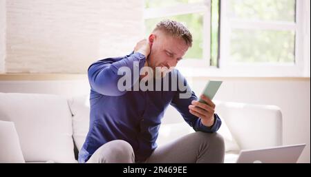 Man With Neck Pain Sitting Using Mobile Phone Stock Photo