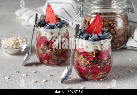 Chocolate granola with strawberries, raspberries and blueberries - healthy breakfast in two glass jars Stock Photo