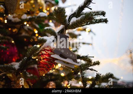 beautiful multi-colored toys on a Christmas tree against the background of lights and snow. Stock Photo