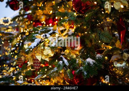 beautiful multi-colored toys on a Christmas tree against the background of lights and snow. Stock Photo