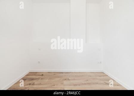An empty bedroom with, white sockets on the wall, wooden floors and plain white painted walls Stock Photo