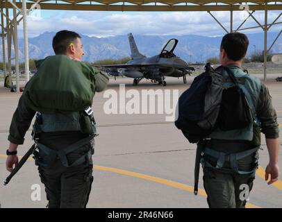 From left, U.S. Air Force 1st Lt. Eric Murray a student pilot, and Lt. Col Jason Ulibarri, an instructor pilot, both assigned to the 149th Fighter Wing, Air National Guard, walk out to an F-16 Fighting Falcon during Coronet Cactus, March 30, 2023, at Davis Monthan Air Force Base, Arizona. The annual training event deploys members of the 149th Fighter Wing, headquartered at Joint Base San Antonio-Lackland, Texas, to another environment in order to familiarize them with accomplishing mission objectives in an unfamiliar location. Stock Photo