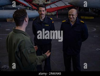 230408-N-SK738-2014 MEDITERRANEAN SEA (April 8, 2023) Lt. Cmdr. Russell Huff, Maintenance Officer, carrier air wing 7, left, gives a tour to Spanish Navy Lt. Carlos Arenas, and Turkish Navy Capt. Guvenc Uysal, distinguished visitors from Standing NATO Maritime Group (SNMG) TWO, aboard the Nimitz-class aircraft carrier USS George H.W. Bush (CVN 77), April 8, 2023. The George H.W. Bush Carrier Strike Group is on a scheduled deployment in the U.S. Naval Forces Europe area of operations, employed by U.S. Sixth Fleet to defend U.S., allied and partner interests. Stock Photo