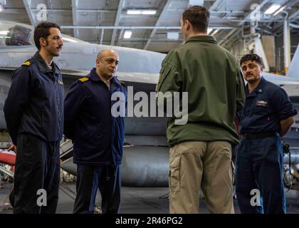 230408-N-OX847-1057 MEDITERRANEAN SEA (April 8, 2023) Lt. Cmdr. Russell Huff, Maintenance Officer, assigned to the Nimitz-class aircraft carrier USS George H.W. Bush (CVN 77), speaks to Turkish Navy Capt. Guvenc Uysal, Chief of Staff, center, and Spanish Navy Lt. Carlos Arenas, both of Standing NATO Maritime Group (SNMG) TWO during a tour of the hangar bay, April 8, 2023. The George H.W. Bush Carrier Strike Group is on a scheduled deployment in the U.S. Naval Forces Europe area of operations, employed by U.S. Sixth Fleet to defend U.S., allied and partner interests. Stock Photo