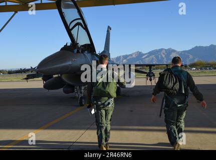 From left, U.S. Air Force 1st Lt. Christopher Einflat, a student pilot, and Maj. Caleb Cienski, an instructor pilot, both assigned to the 149th Fighter Wing, Air National Guard, walk out to an F-16 Fighting Falcon during Coronet Cactus, March 29, 2023, at Davis Monthan Air Force Base, Arizona. The annual training event deploys members of the 149th Fighter Wing, headquartered at Joint Base San Antonio-Lackland, Texas, to another environment in order to familiarize them with accomplishing mission objectives in an unfamiliar location. Stock Photo