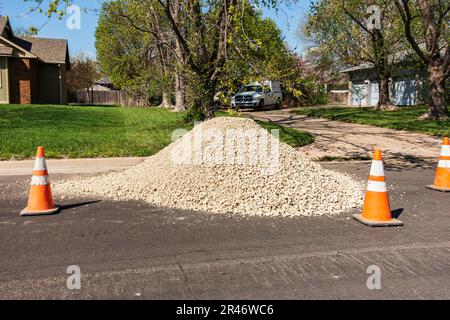 A pile of rocks for landscaping or construction in the street with orange traffic cones marking it off. Kansas, USA. Stock Photo