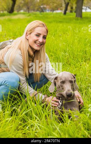 Portrait of weimaraner with his mistress in the park. Young woman walking the dog. Concept of leisure and healthy life in nature Stock Photo