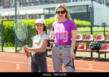 Mother smiling broadly. Mother smiling broadly before playing tennis with her lovely beaming daughter. Stock Photo