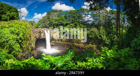 A lush tropical jungle backdrop featuring a majestic waterfall cascading down a rocky face. Hawaii. Stock Photo