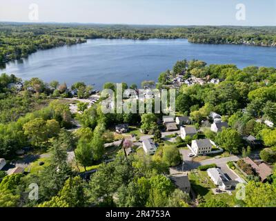 A drone view of Lake Attitash surrounded by greenery on a sunny day in Massachusetts Stock Photo