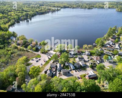 A drone view of Lake Attitash surrounded by greenery on a sunny day in Massachusetts Stock Photo