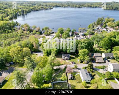 A drone view of Lake Attitash surrounded by greenery on a sunny day in Massachusetts Stock Photo