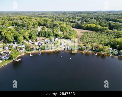 A drone view of Lake Attitash surrounded by greenery on a sunny day in Massachusetts Stock Photo