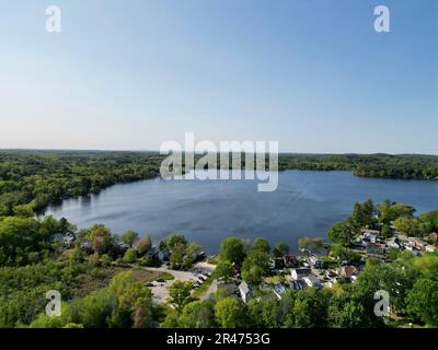 A drone view of Lake Attitash surrounded by greenery on a sunny day in Massachusetts Stock Photo