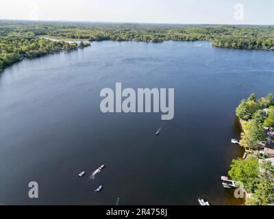 A drone view of Lake Attitash surrounded by greenery on a sunny day in Massachusetts Stock Photo