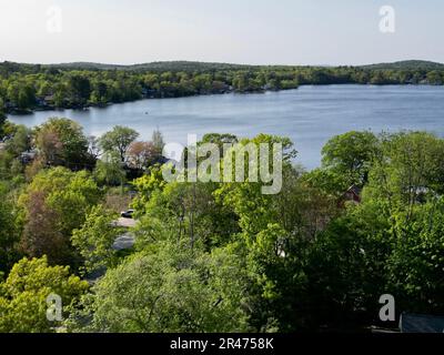 A drone view of Lake Attitash surrounded by greenery on a sunny day in Massachusetts Stock Photo