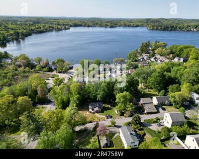 A drone view of Lake Attitash surrounded by greenery on a sunny day in Massachusetts Stock Photo