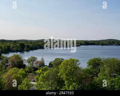 A drone view of Lake Attitash surrounded by greenery on a sunny day in Massachusetts Stock Photo