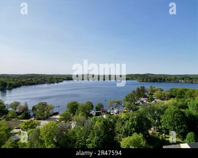 A drone view of Lake Attitash surrounded by greenery on a sunny day in Massachusetts Stock Photo