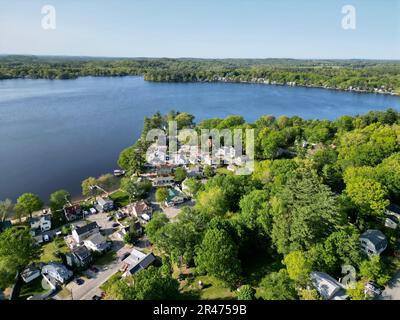 A drone view of Lake Attitash surrounded by greenery on a sunny day in Massachusetts Stock Photo